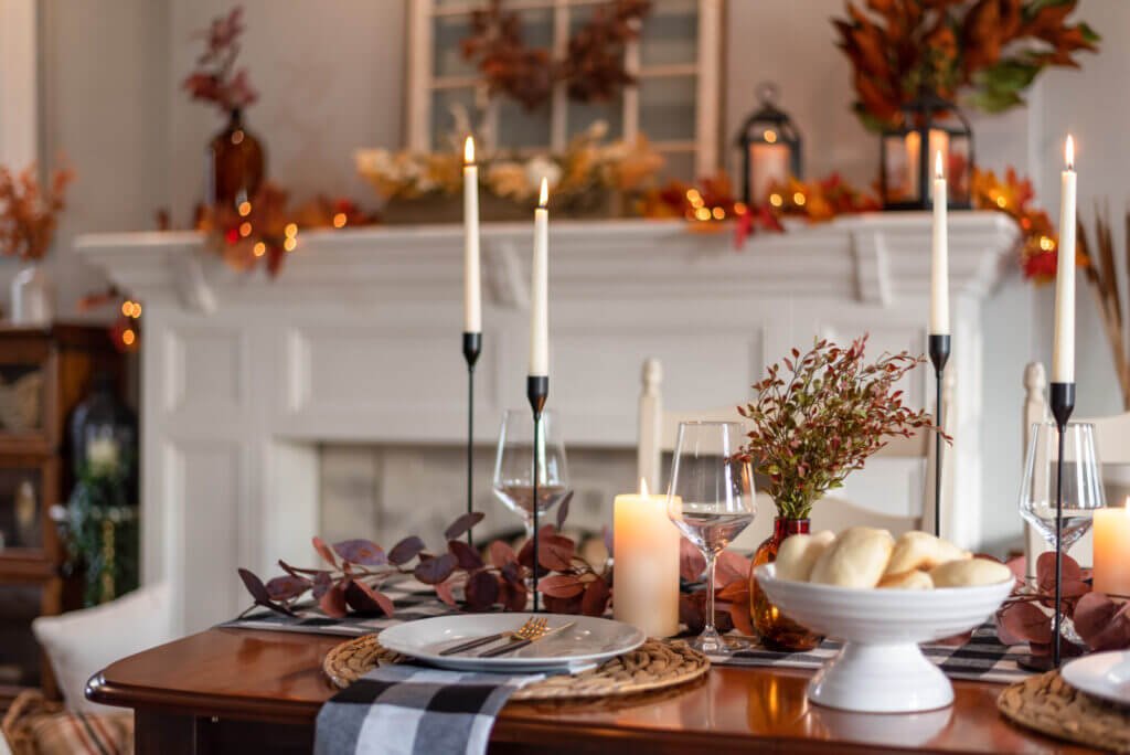 Beautiful dining room decor sits atop a table, including lit candles, leaf decorations, elegant place settings and more.